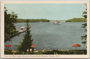 Vintage postcard of a lake scene with a dock and boats, featuring a scenic view from Main Lodge, Cleveland's House, Minett, Muskoka, Canada.